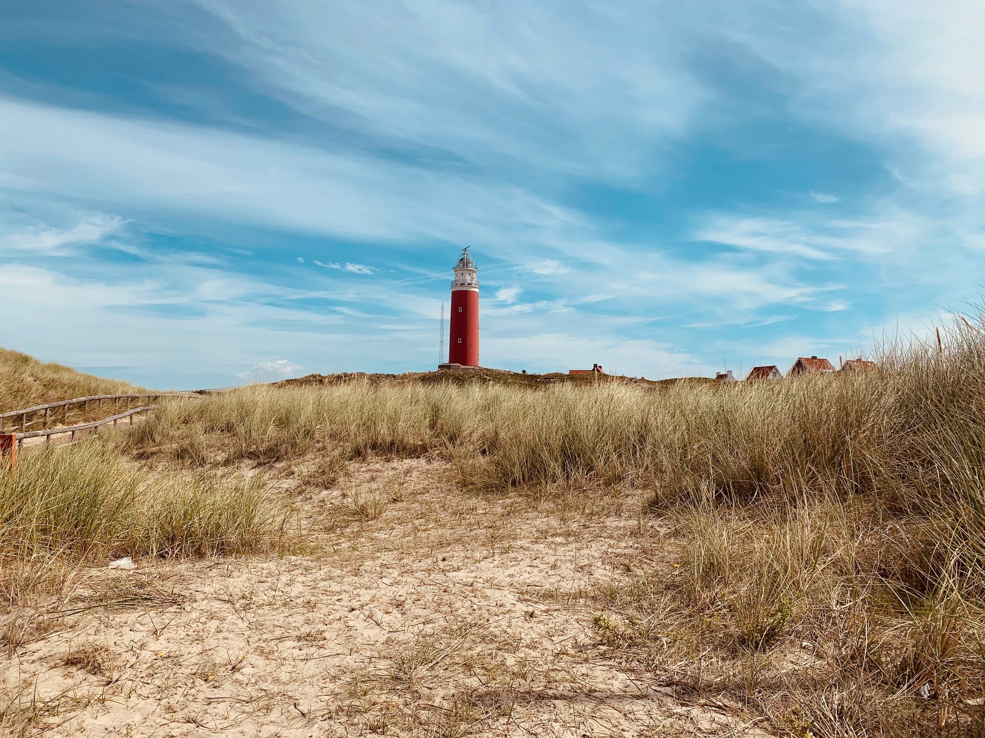 Rode vuurtoren tussen de duinen aan de kust